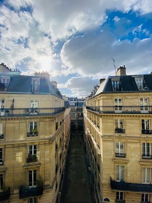 A narrow street flanked by historic buildings with balconies and a central alleyway. - Queens Boutique Hotel (Paris)