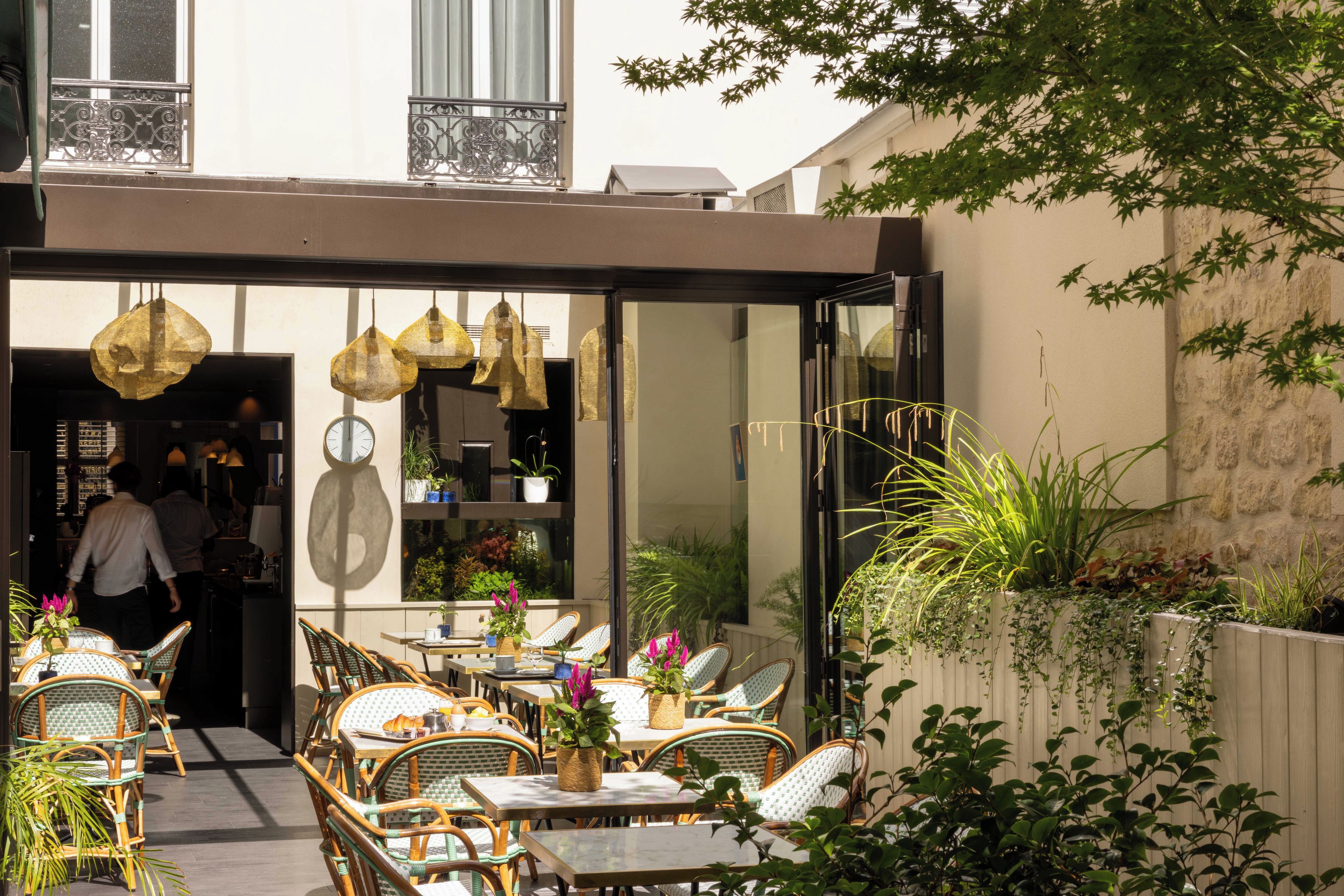 Een terras met rieten meubels en hangende lichten.