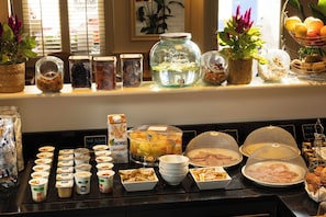 A breakfast buffet with various food items and containers. - Hôtel Muguet (Paris)