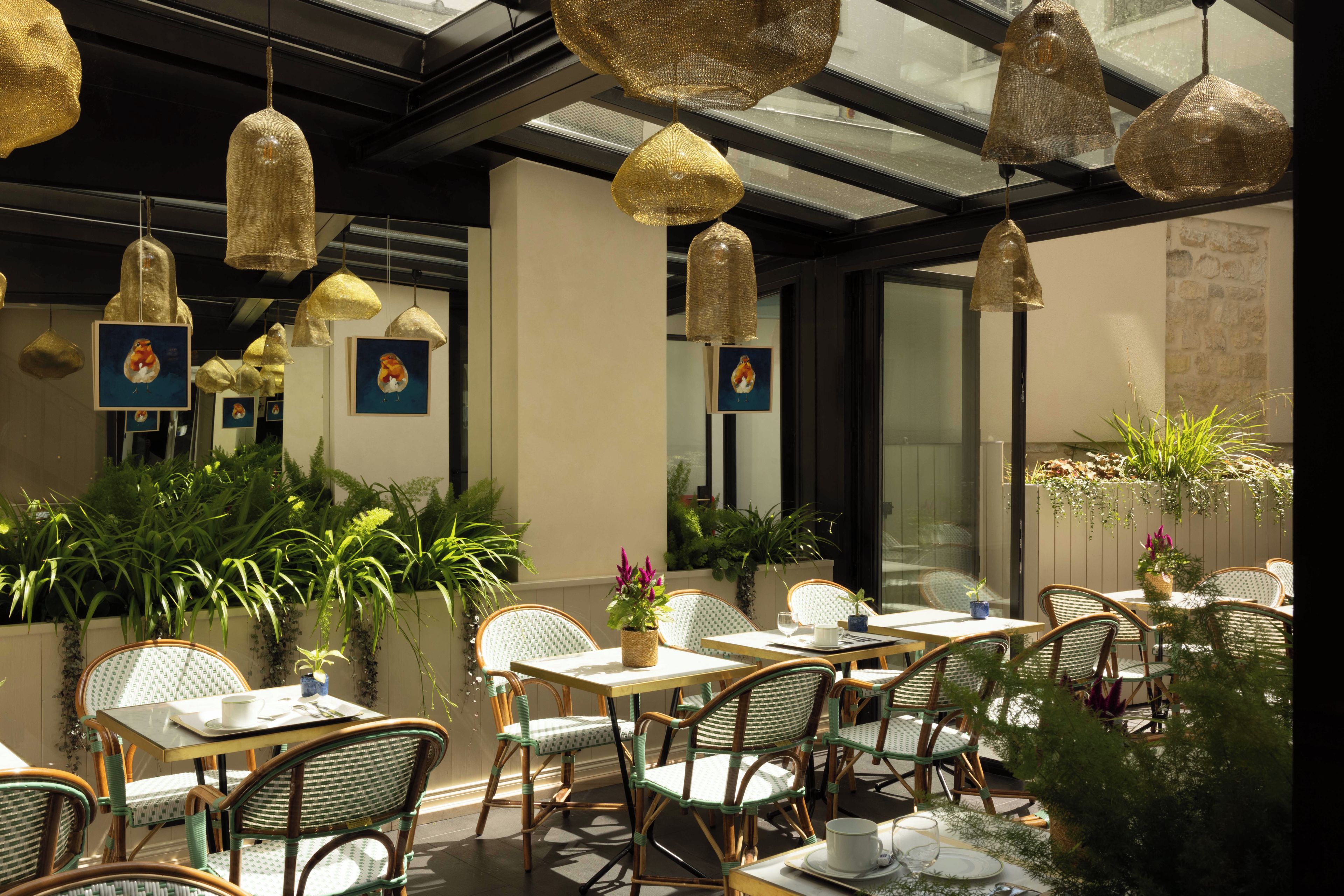 An indoor dining area with wicker furniture, hanging pendant lights, and framed artwork on the walls.