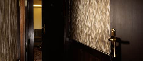 A hallway with a patterned wall and a door with a brass handle.