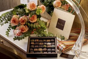 A chocolate box, a bouquet of roses, and a gift bag on a table. - Hôtel Muguet (Paris)