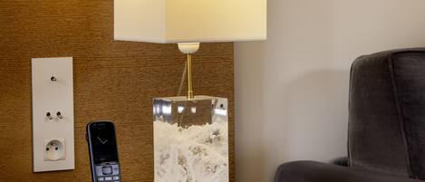 Une chambre d’hôtel avec une table de chevet sur laquelle se trouvent un téléphone portable et une lampe décorative.