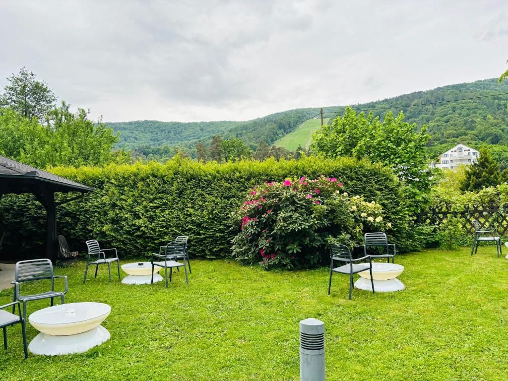 A well-maintained garden with a seating area, surrounded by lush greenery and a view of rolling hills.