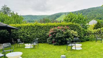 A well-maintained garden with a seating area, surrounded by lush greenery and a view of rolling hills.