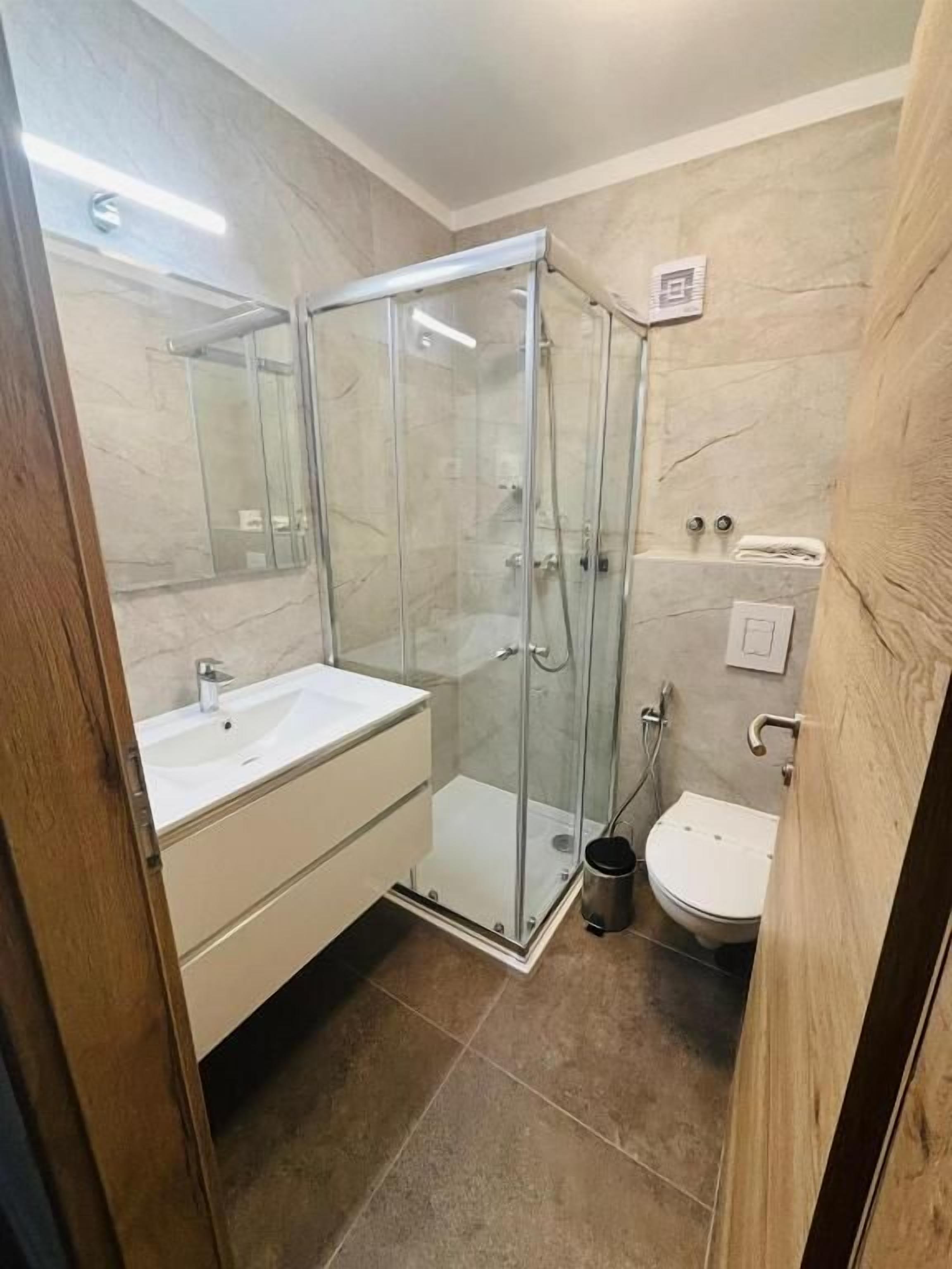 Une salle de bain avec une douche à parois de verre, un lavabo blanc et des toilettes.