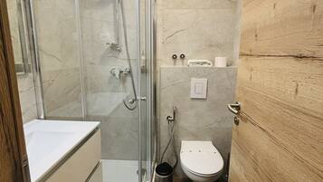 Un baño pequeño con cabina de ducha de vidrio, inodoro y lavamanos.