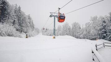 A snowy ski lift with a cable car in motion, surrounded by snow-covered trees.