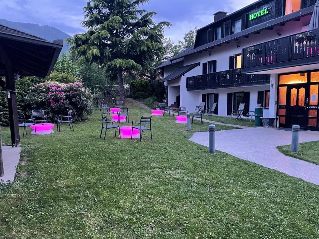 Un hotel con un área de estar al aire libre techada, un camino que lleva a la entrada y vistas de la vegetación circundante.