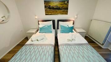 A hotel room with two beds, each with a headboard, a bedside table, and a wall-mounted picture.