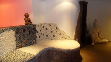 A room with a unique stone-textured sofa, a statue, and a draped curtain.