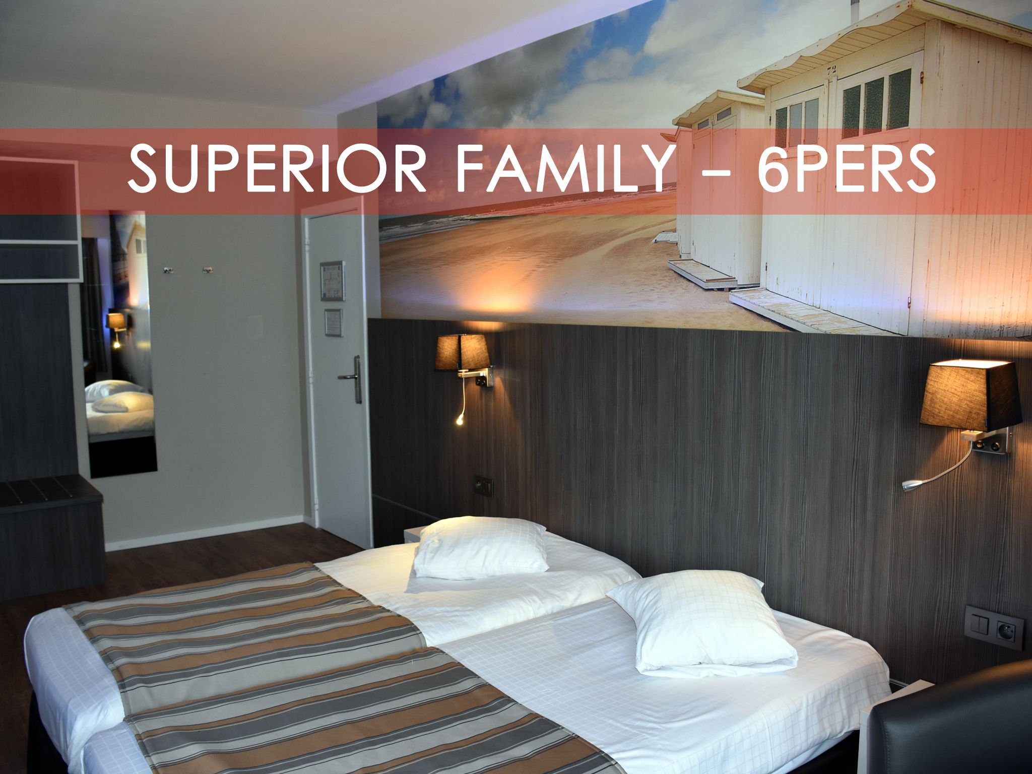 A hotel room with a bed, a desk, and a mirror. There is a wall with a painting and a lamp.
