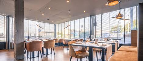 A spacious restaurant with high ceilings, large windows, and modern lighting fixtures.