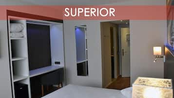 Une chambre d’hôtel équipée d’un lit, d’une armoire, d’un miroir, d’une porte et d’une lampe fixée au mur.