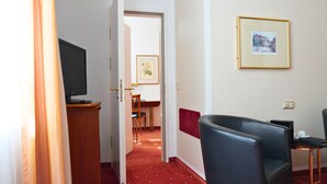 Une chambre d’hôtel équipée d’une télévision, d’un bureau avec une chaise, d’un tableau encadré au mur et d’un mur d’accent de couleur rouge.