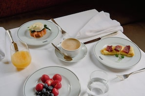 A table set with a breakfast of eggs, smoked salmon, coffee, and fruit. - Gebhards Hotel (Goettingen)