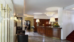A spacious lobby with a reception desk, a chandelier, and a black leather sofa. - Gebhards Hotel (Goettingen)