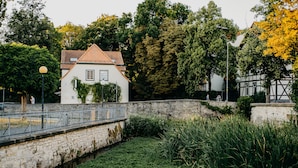 A historic building with a tiled roof, a stone wall, and a narrow water channel. - Gebhards Hotel (Goettingen)