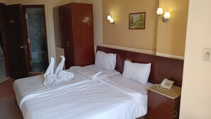 A hotel room with a neatly made bed, a wooden wardrobe, a bedside telephone, and wall-mounted lights. - Susanna (Luxor)
