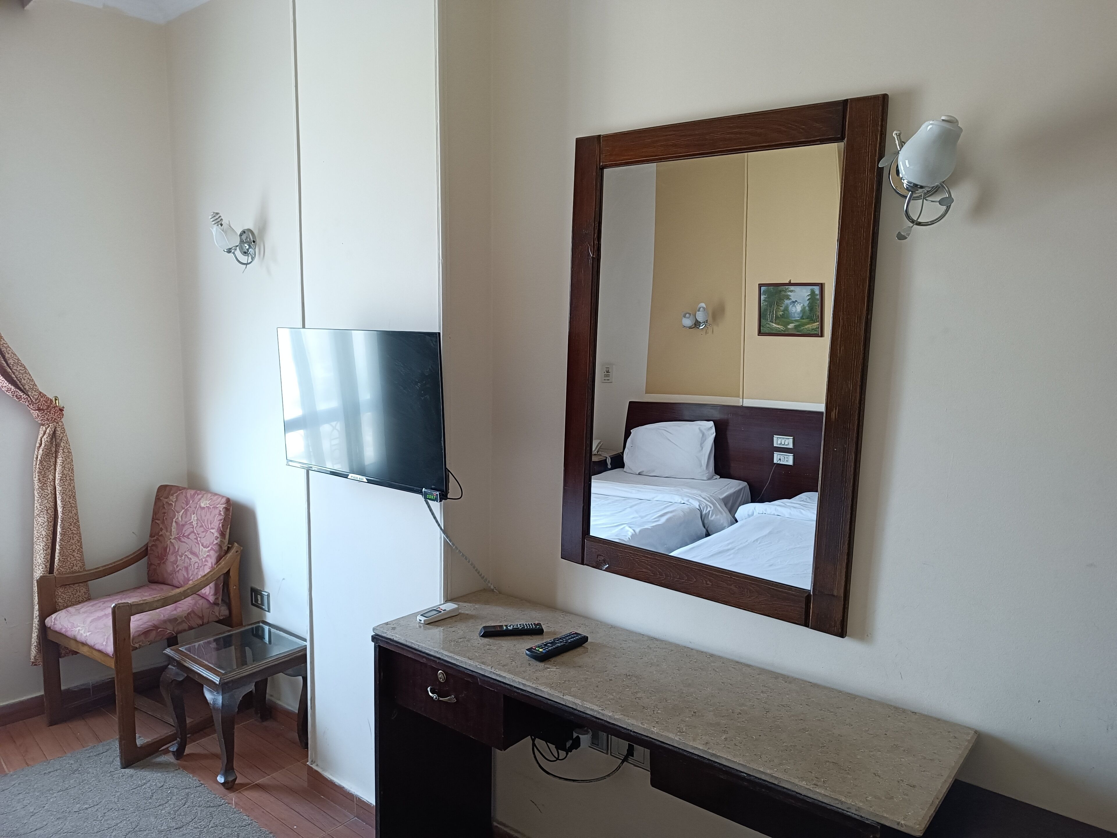 A hotel room with a bed, a TV, a desk, a chair, and a mirror.