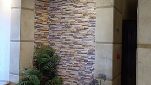 A lobby with a stone-patterned wall, potted plants, and a tiled floor. - Susanna (Luxor)