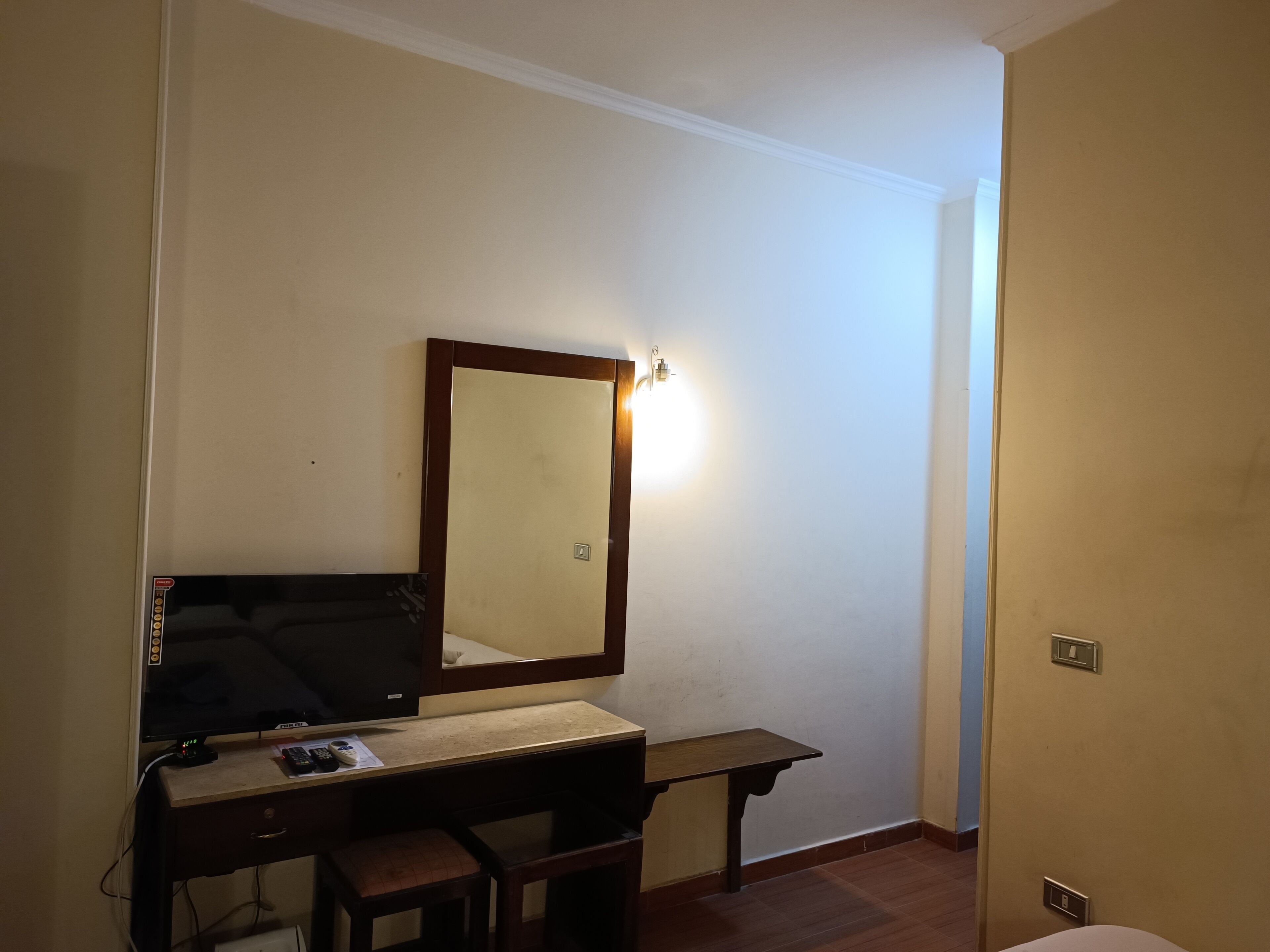 Una habitación pequeña y sencilla con escritorio, silla y espejo.