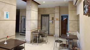 A hotel lobby with multiple seating areas, a reception desk, and an elevator. - Susanna (Luxor)
