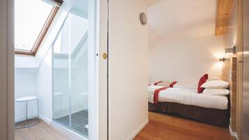 Un dormitorio con una cama, una mesita y un box de ducha de cristal.