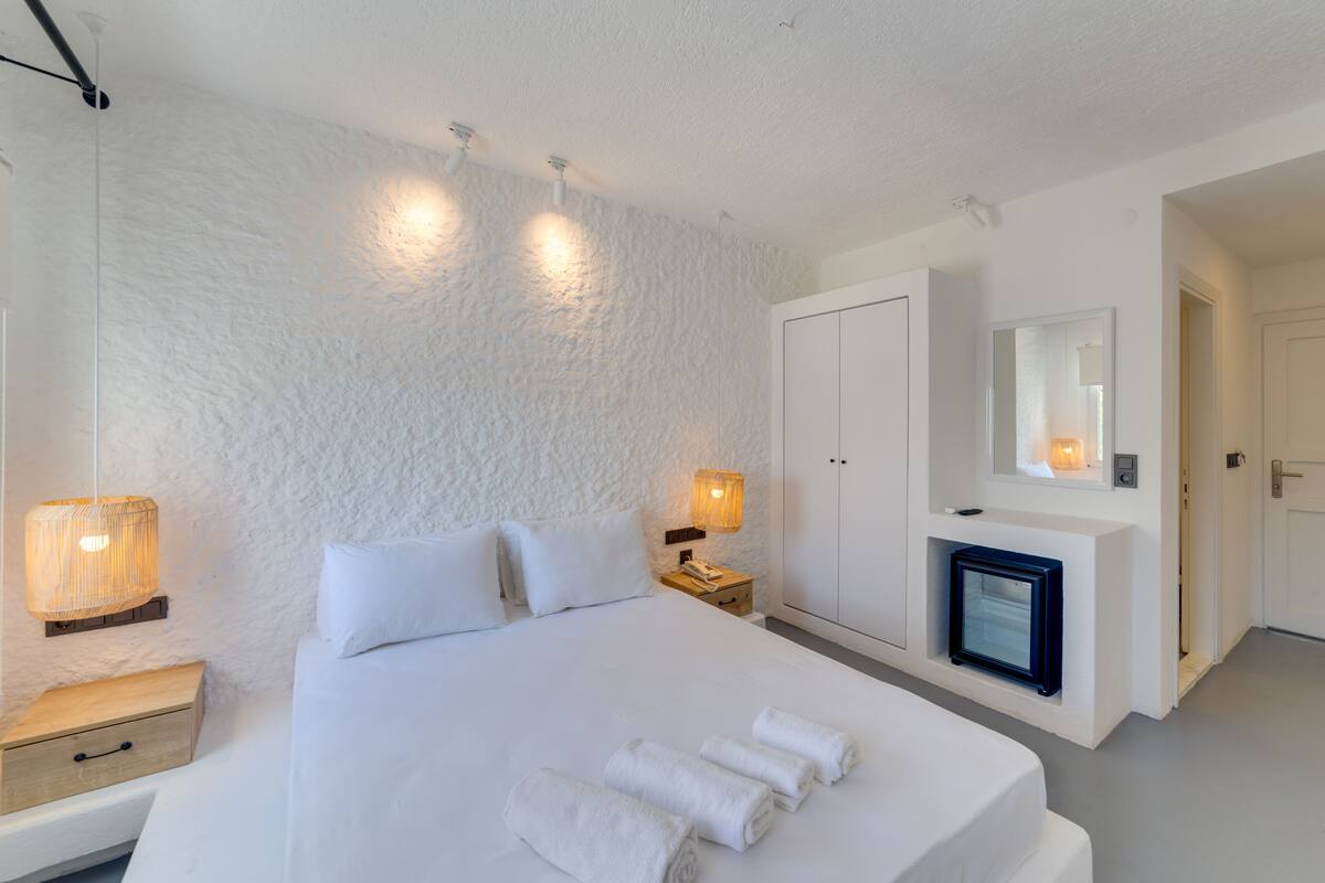 Une chambre à coucher avec un grand lit, des lampes de chevet, une table de chevet, une armoire et un miroir.