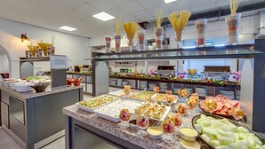 Un bufé con diversas opciones de comida y bebidas, como pasta, ensaladas y fruta.