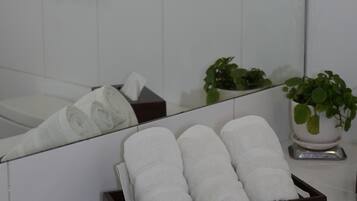 A bathroom with a mirror, towel rack, and a plant.
