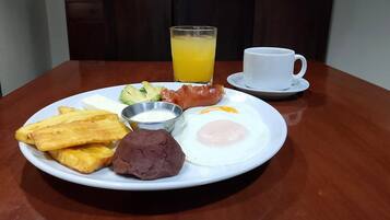 A breakfast plate with eggs, beans, avocado, and toast on a wooden table.