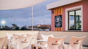 A terrace with white chairs and a sign for 'Alghero Rugby'.