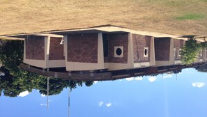 A building with a brick facade and a circular window, reflected in a body of water.