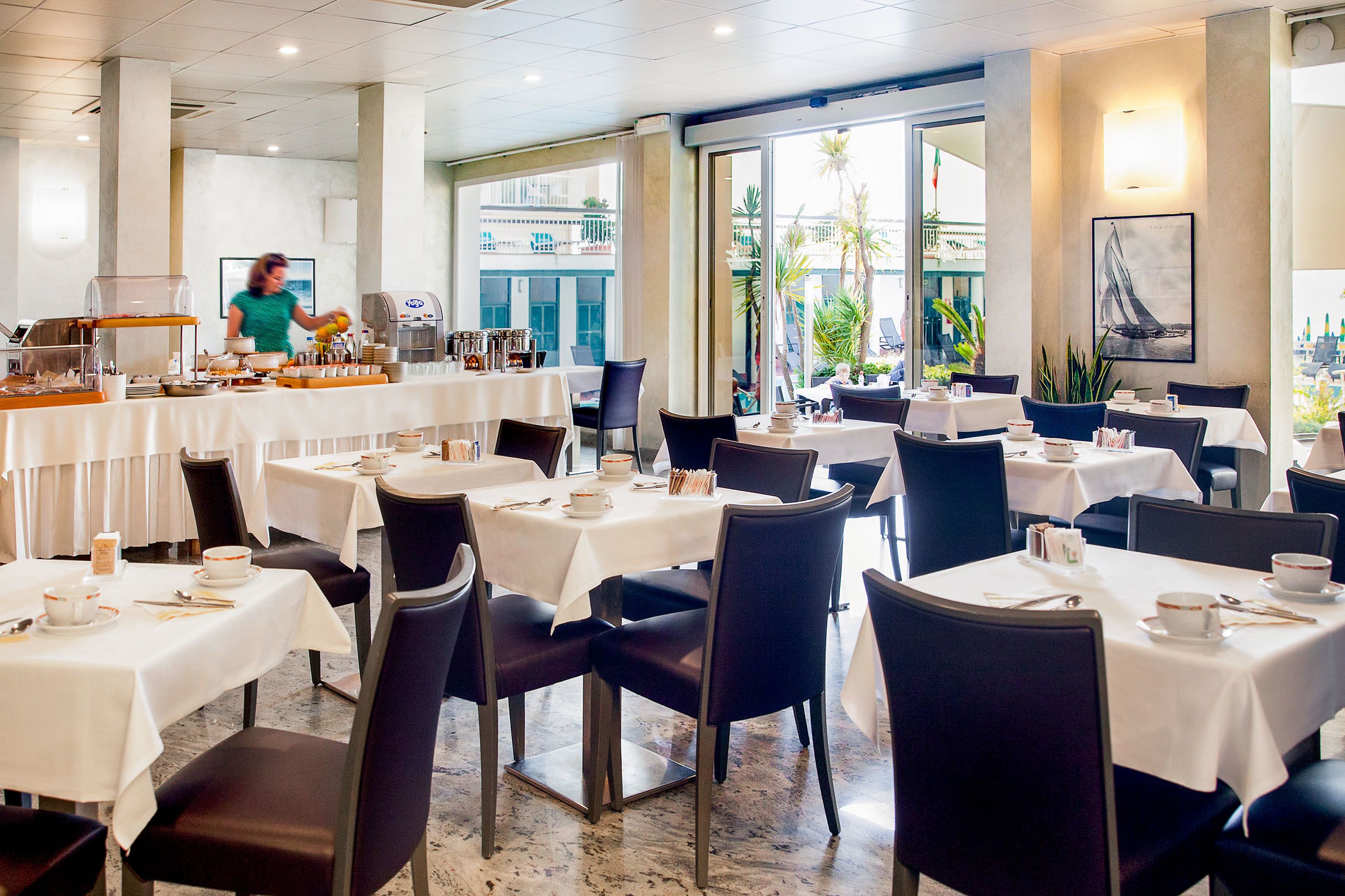Un restaurante con varias mesas y sillas, una barra de servicio y vistas al exterior.