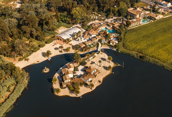 An aerial view of a coastal resort with villas, a swimming pool, and a beach area.