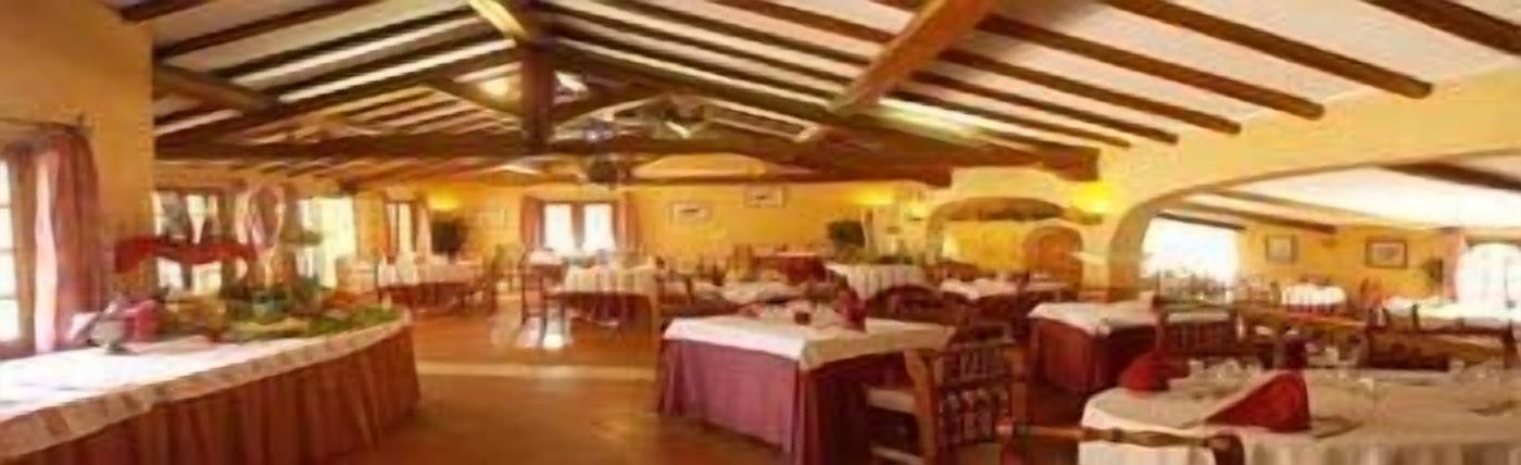 Un comedor espacioso con techos altos y vigas de madera, con varias mesas dispuestas para comer.