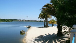 A beach with calm water, palm trees, and a clear sky. - Quinta da Lagoa (Mira)