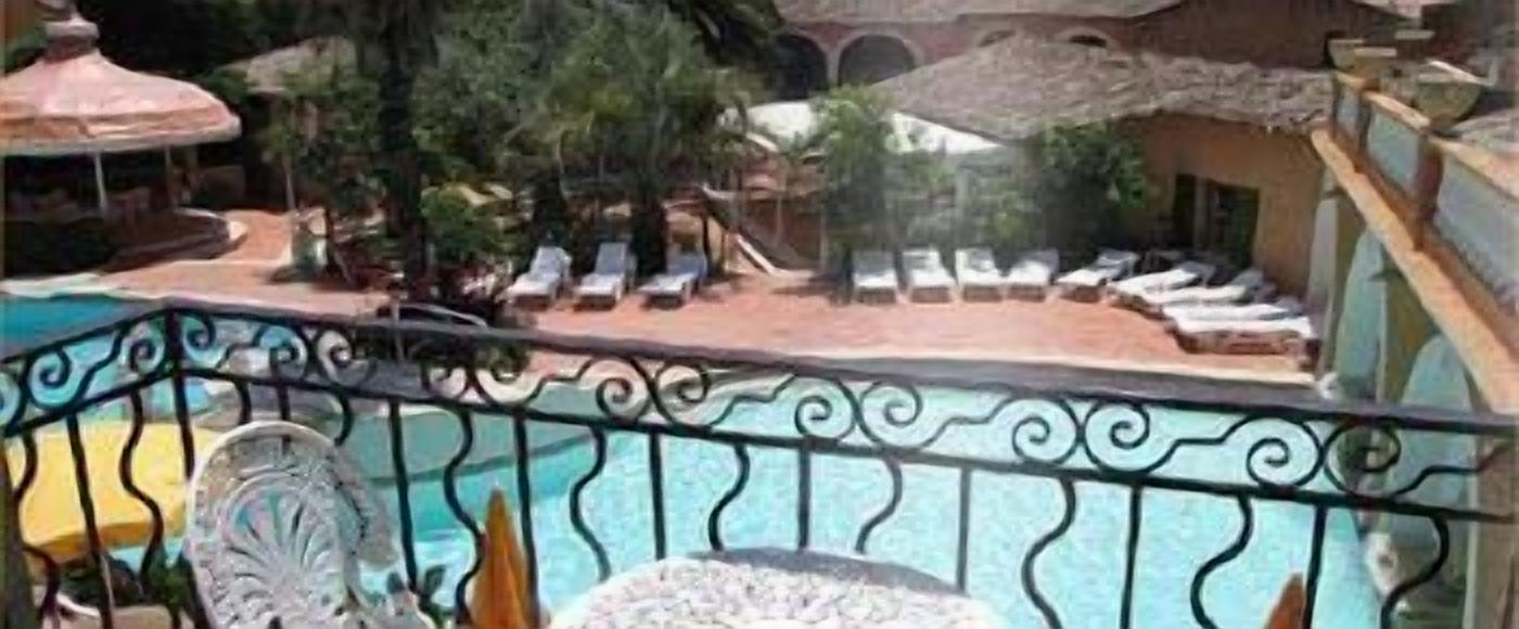 A pool area with lounge chairs and a decorative fence.