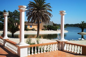 A coastal property with a pool, palm trees, and a beach.