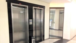 A hallway with two elevators and a trash bin. - Umbu Hotel Porto Alegre (Porto Alegre)