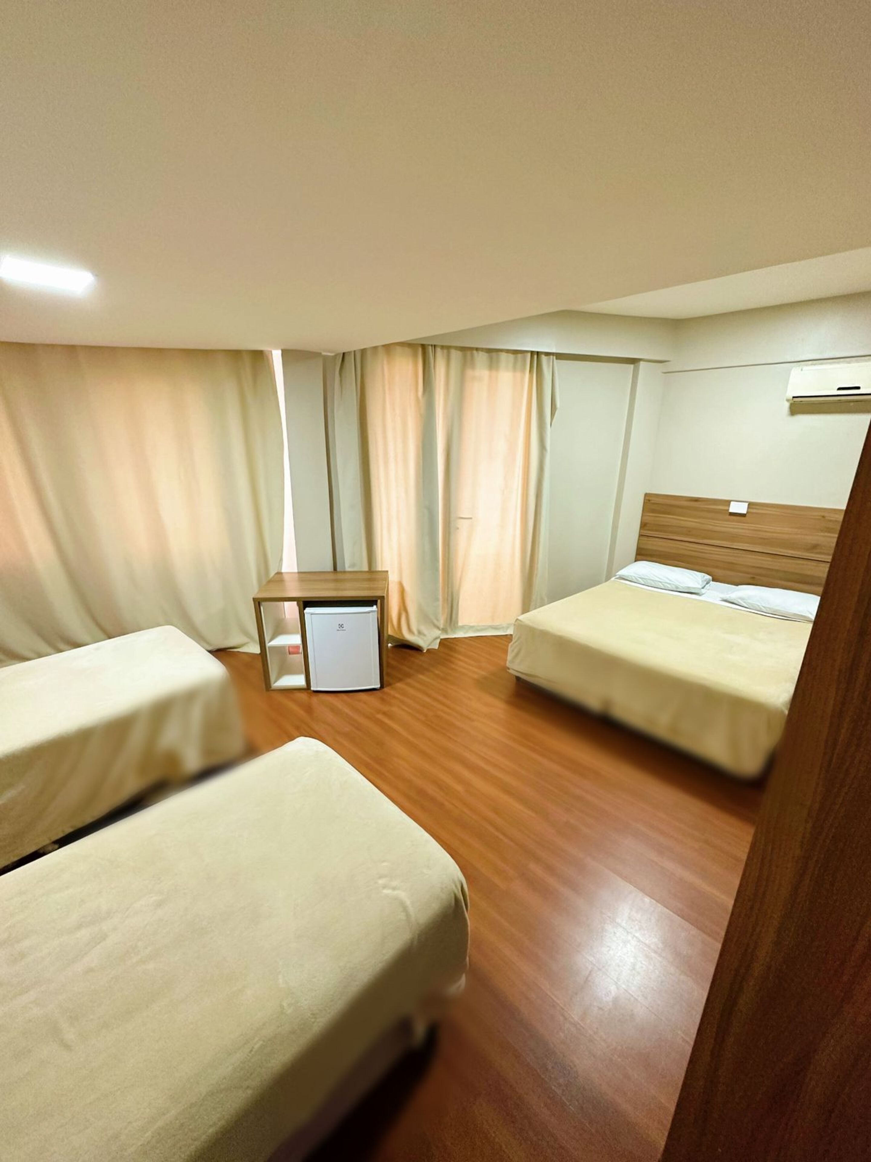 Habitación de hotel con dos camas, un escritorio pequeño y un refrigerador.