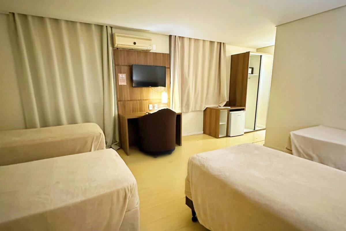 A hotel room with two beds, a television, a desk, and a chair.