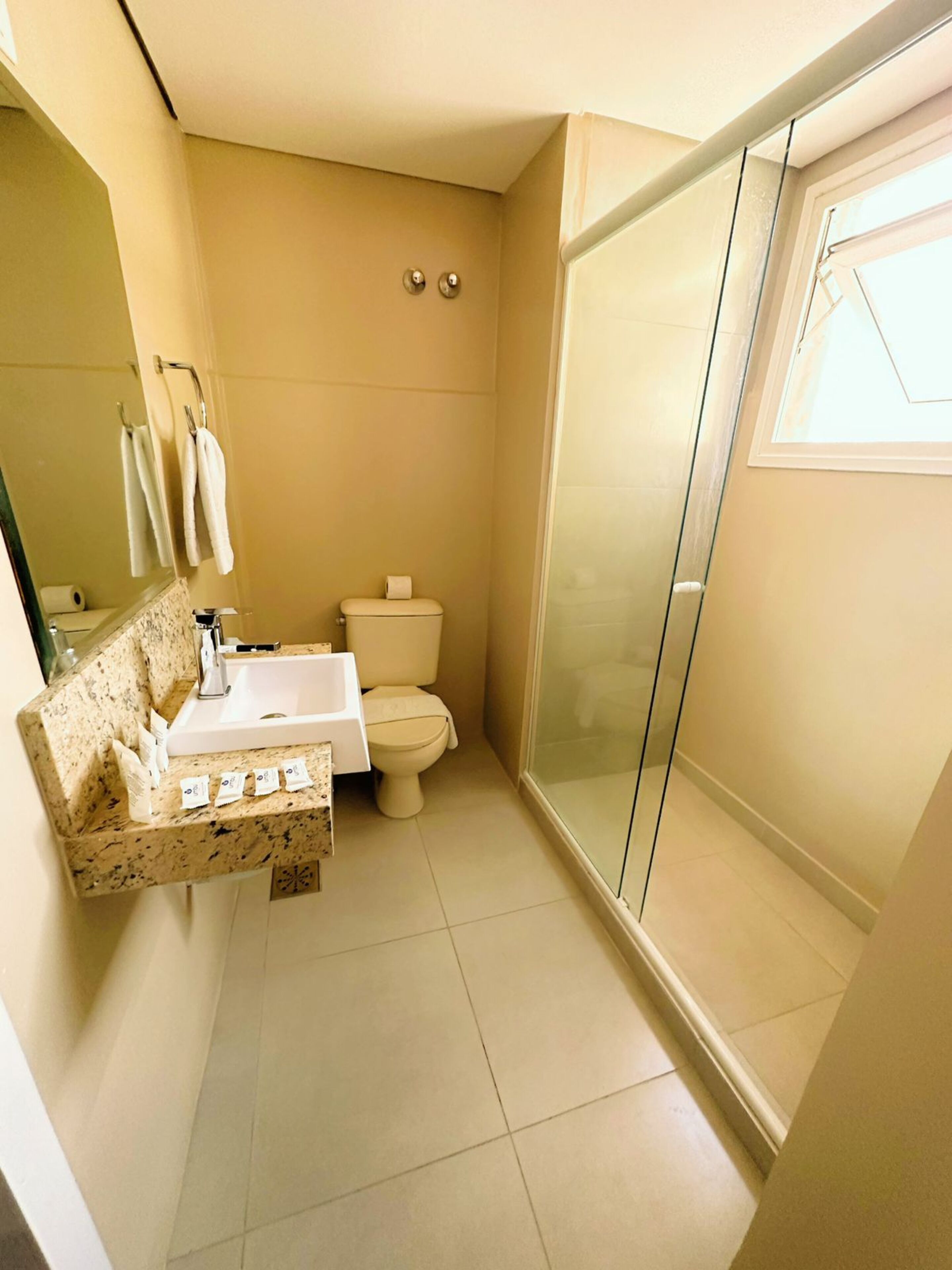 A bathroom with a sink, toilet, and glass shower enclosure.
