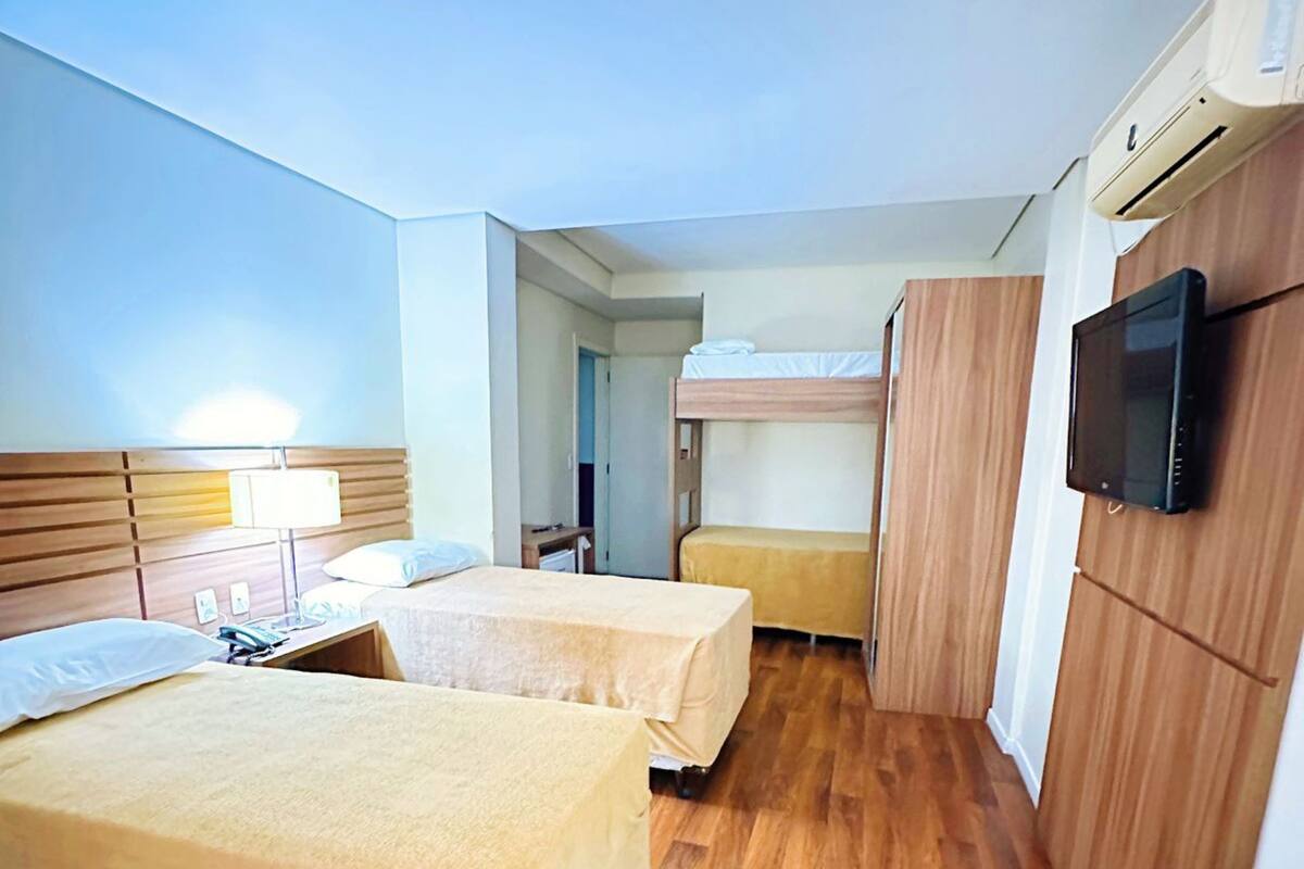 A hotel room with two beds, a desk, a TV, and a wardrobe.