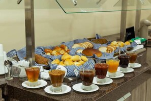 Un bufé con panes, pasteles y bebidas variados.