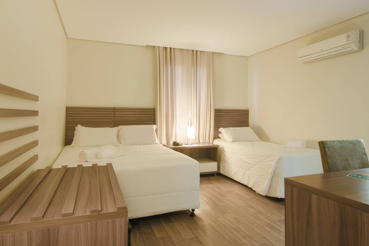 A hotel room with a bed, bedside tables, a desk, and a chair.