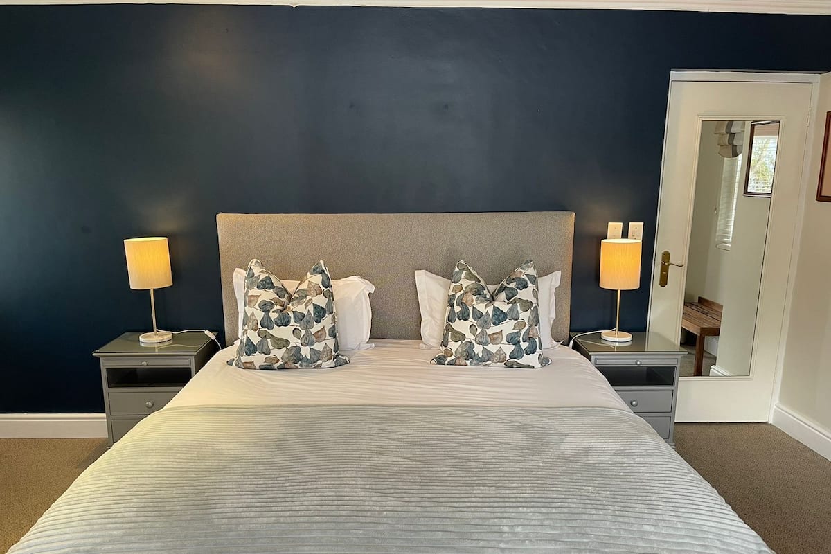 A neatly made bed with a striped bedspread, two matching pillows, and two bedside lamps.