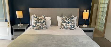 A neatly made bed with a striped bedspread, two matching pillows, and two bedside lamps.