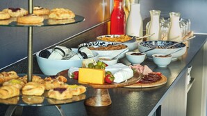 Un bufé con diversas opciones de comida, como pasteles, queso y frutas.